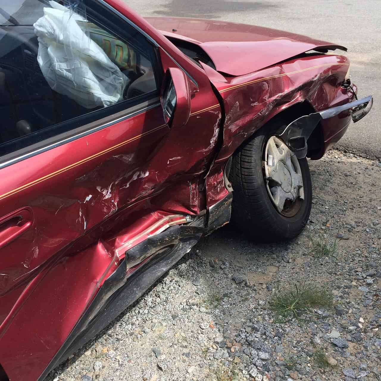 Roter Pkw mit eingedrückter Seite und ausgelöstem Airbag nach einem Unfall