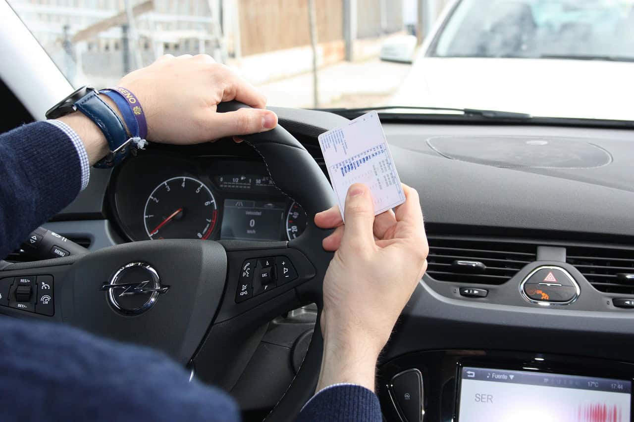 Hand hält eine Führerscheinkarte am Lenkrad